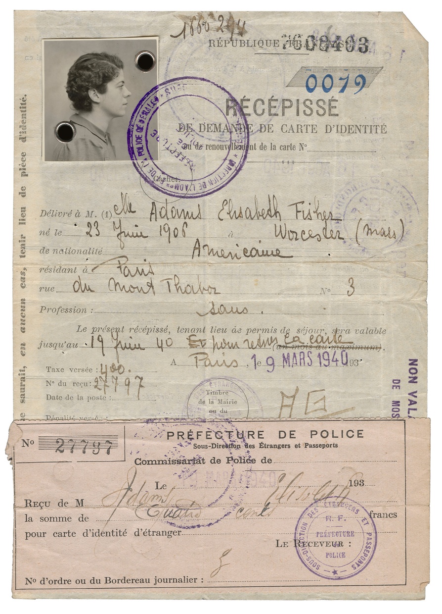 A sheet of paper has writing in French and a photograph of a 34 year-old light-skinned woman taken from the side attached on the upper left of the page. The page has handwritten text written on it, with stamps on it.