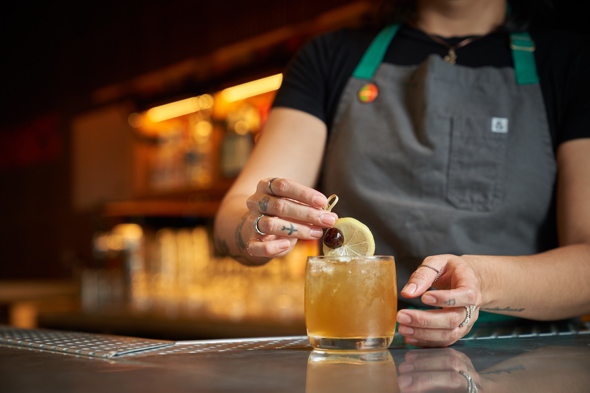 Image of a bartender decorating a cocktail with a lemon and cherry.