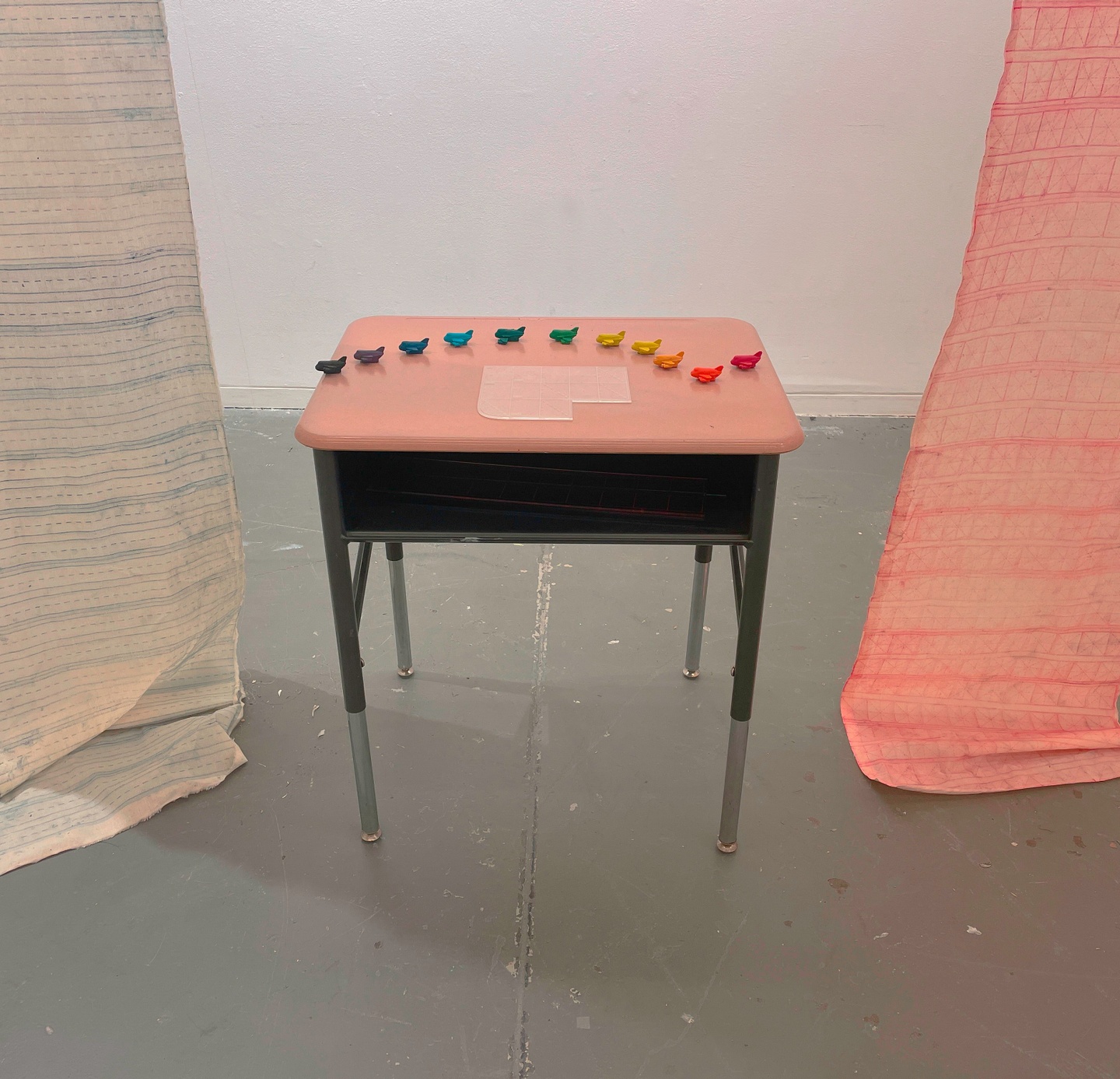 A closeup of the desk with the small rainbow airplanes and a small plastic mat on the desk.