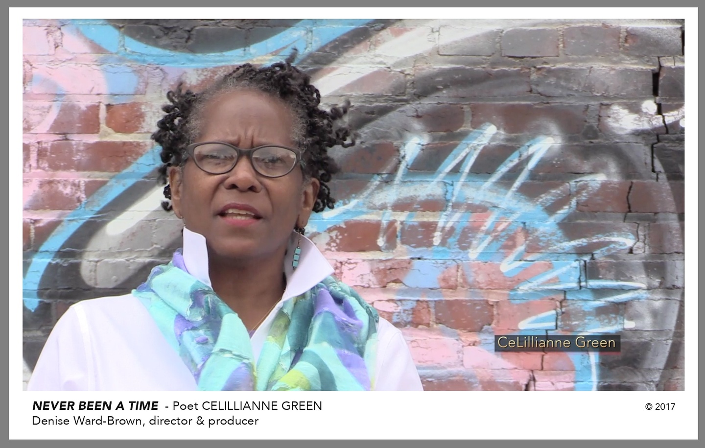 Text reads, "NEVER BEEN A TIME - Poet CELILLIANNE GREEN", below a still from the video, in which Green is filmed in front of a spray painted brick wall. Green wears a white collared shirt, black framed glasses, and a colorful, cool-toned scarf.