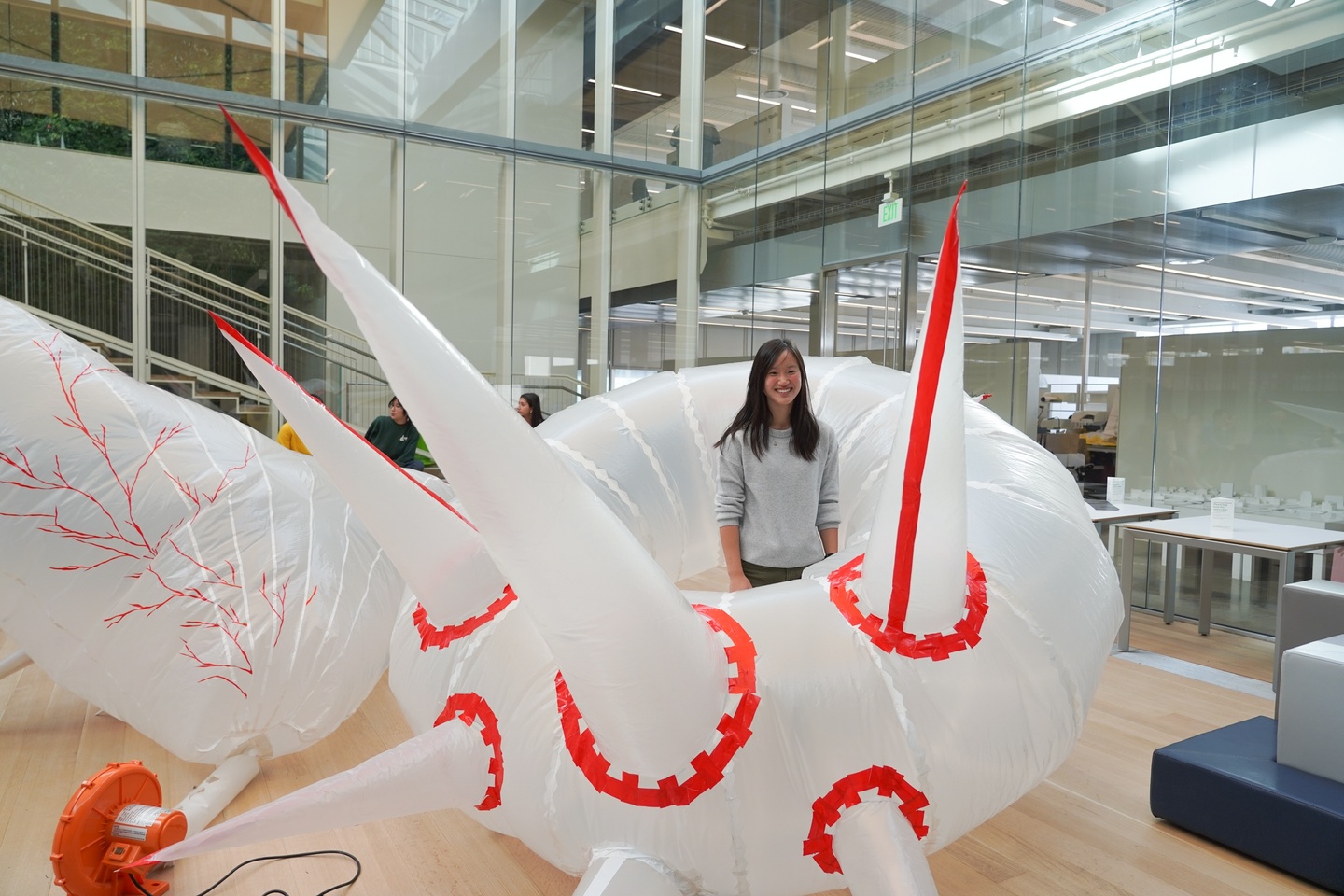 Student stands inside a giant inflatable in the shape of a donut with 5 foot long spikes protruding from it.