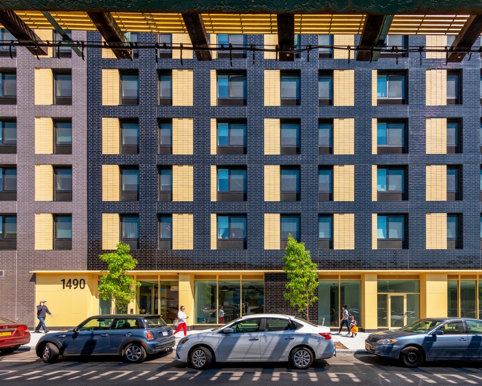 Exterior facade of a multistory affordable housing unit with an alternating pattern of dark brick and light yellow brick.