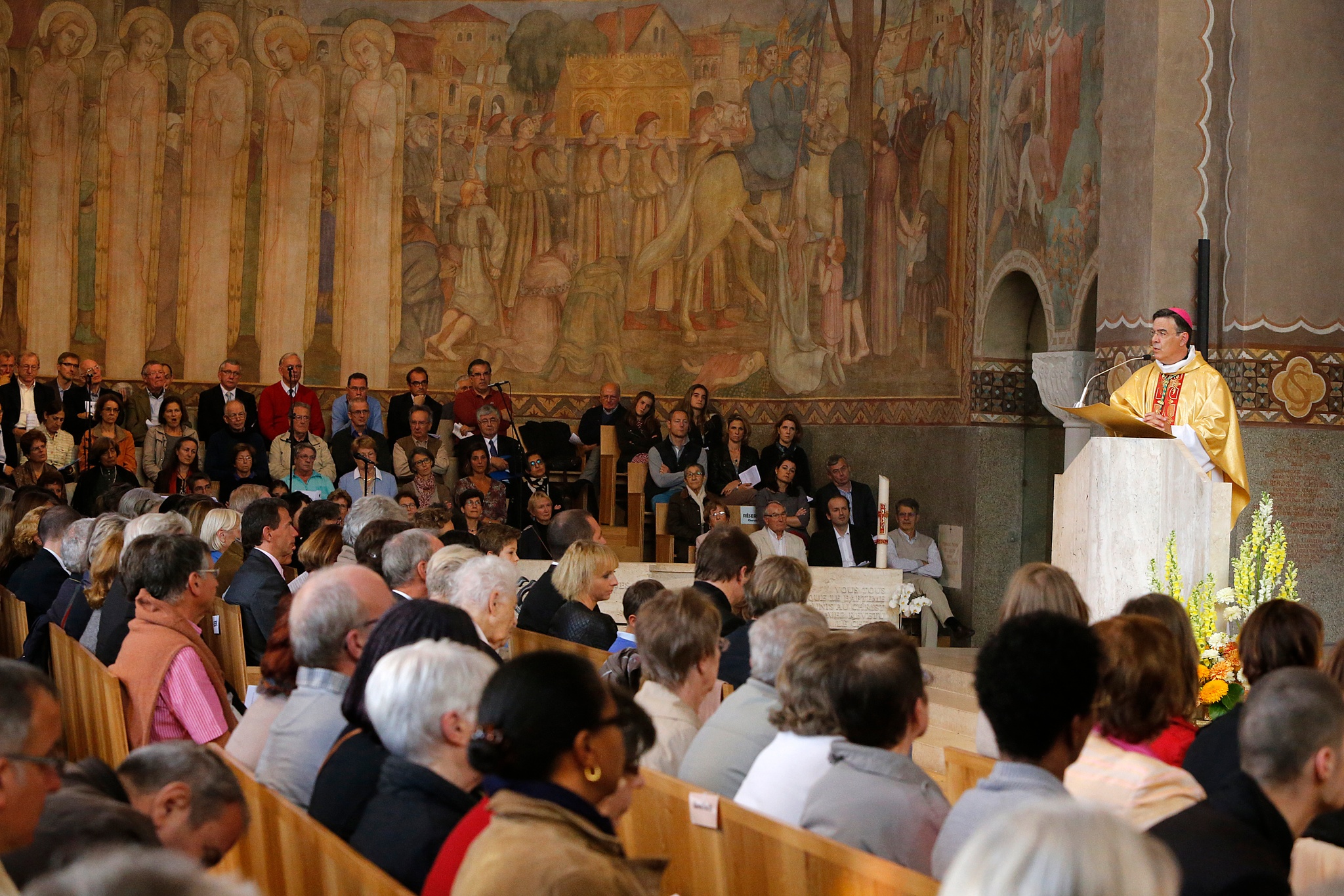 A priest at a lectern in a church in front of a seated congregation
