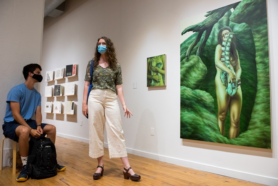 An artist stands in front of her large painting