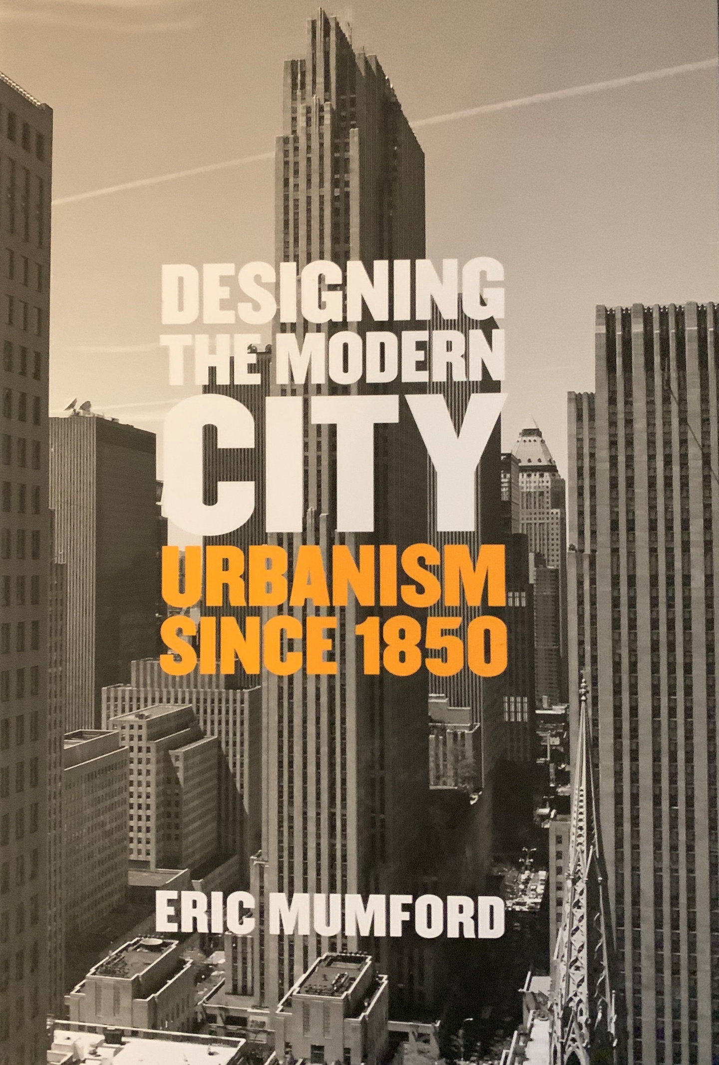Cover of Designing the Modern City: Urbanism Since 1850, with a black-and-white photo of a cityscape with white and orange type over the top.